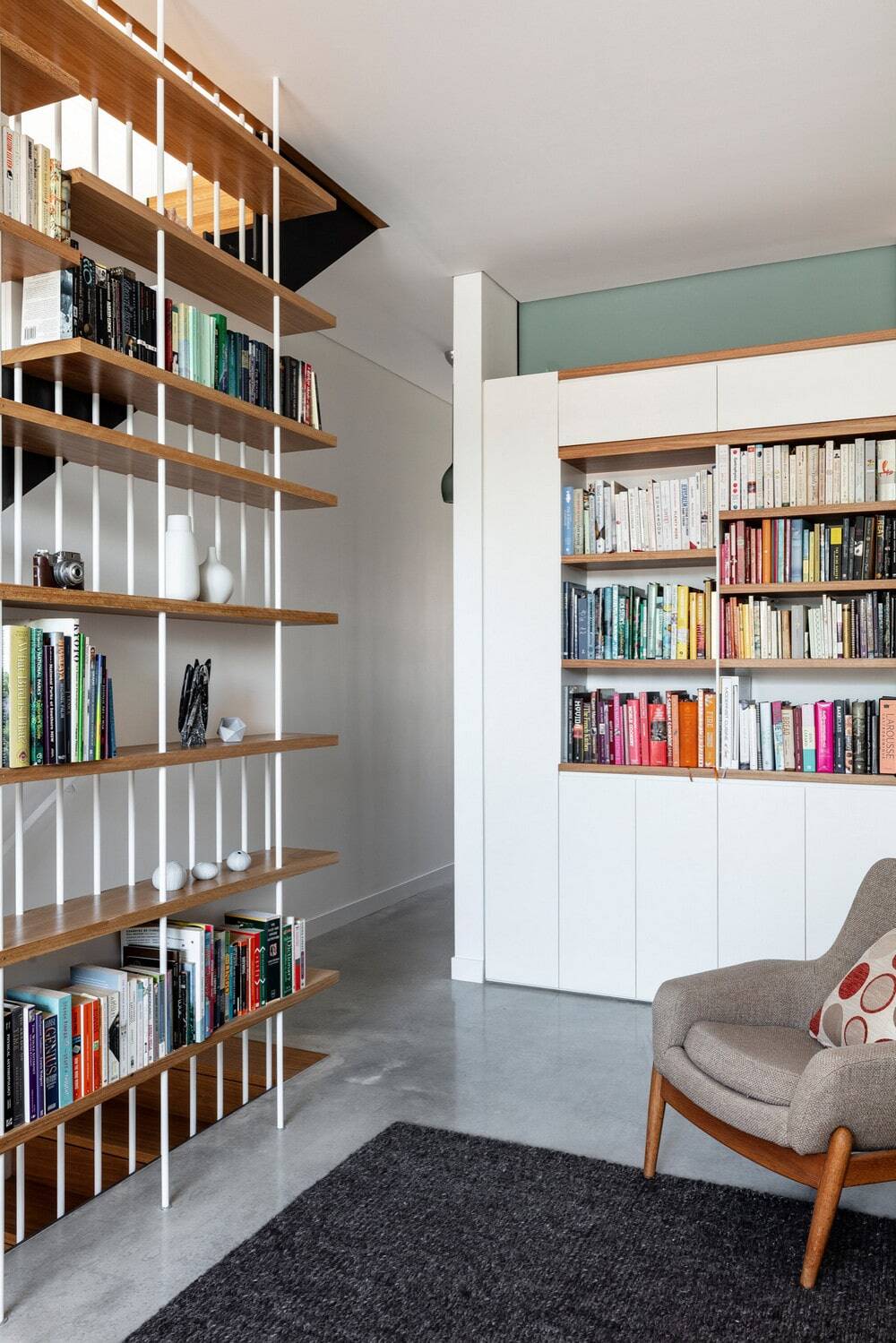 loft-style family room with a library, white walls, concrete floors and grey floor, Anderson Architecture