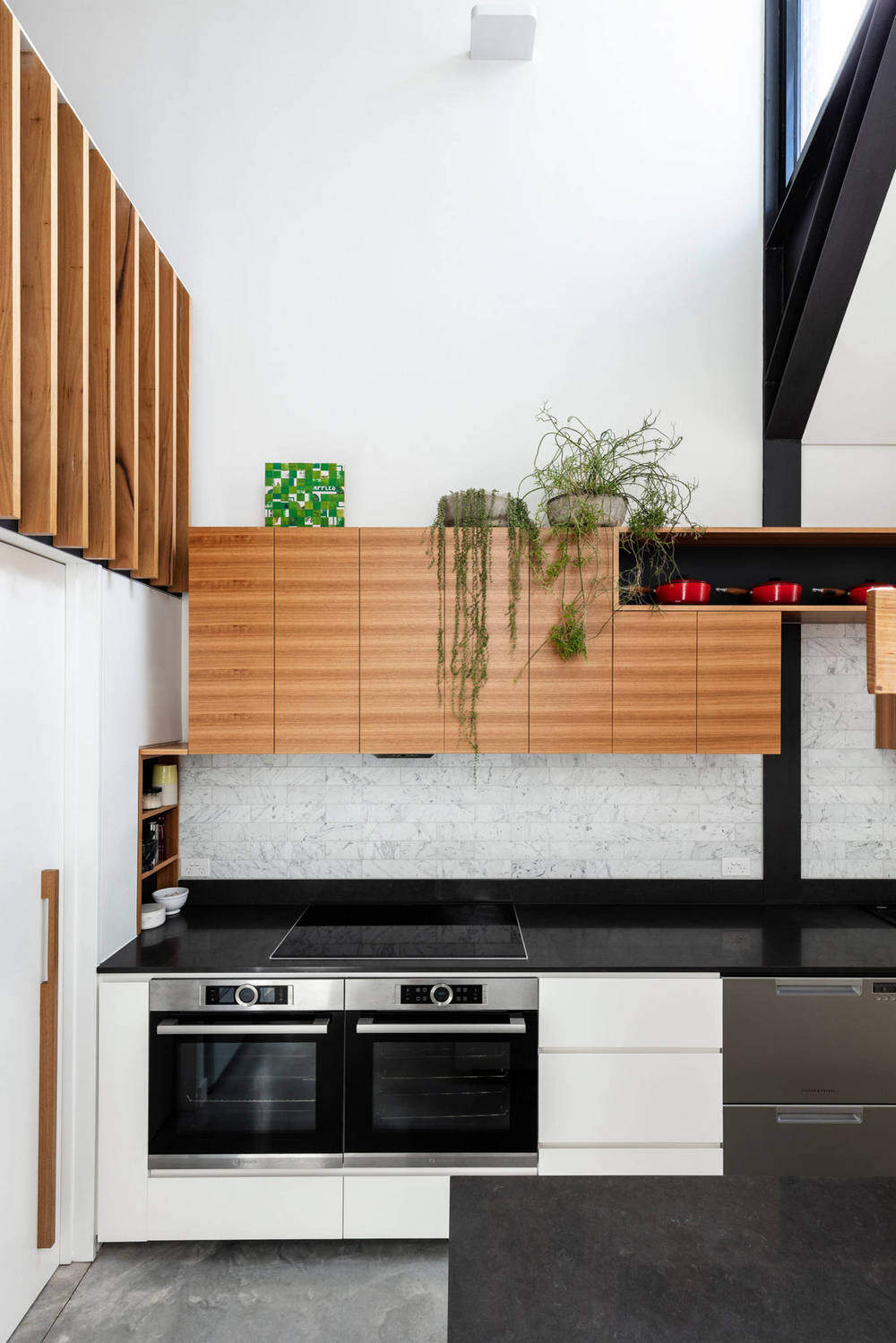 double-bowl sink, flat-panel cabinets, white cabinets, quartz benchtops, grey splashback, stainless steel appliances, concrete floors, with island, grey floor and black benchtop