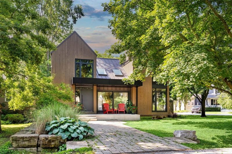 A sophisticated, yet playful cottage bringing Scandinavian flare to beautiful Niagara-on-the-Lake ON. Located on a beautifully landscaped corner lot, just minutes from the downtown core. A compelling transformation, smpl rejuvenated a 1980s residence, melding a coordinated blend of Scandinavian influence externally, and playful sophistication within. Crafting a balance of neutral wood tones through vertical siding, the exterior creates an intimate connection with its scenic lakeside locale. The interior palette layers hues of oyster and sand, weaving an organic visual continuation of the exterior, with its vertical lines and organic shapes. The unique layout provides a flow that is ideal for cooking and entertaining, with the kitchen at the center, and all adjacent spaces — such as the built-in breakfast bar and the designated coffee station — branching from it. The updated and reimagined double-sided fireplace unifies separate living and dining areas. A triangular second-floor addition, with its uniquely shaped angled ensuite, elevates this home into a functional, stylish, and calm escape from urban rigors.